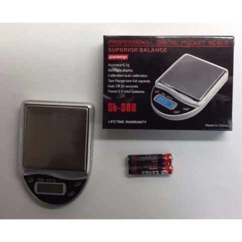 The SB 500 Scale 500g x 0.1g features a stainless steel platform and comes with its packaging box and two AAA batteries. It includes a backlight display for easy reading, ensures precise calibration, offers a lifetime warranty, and has a compact design wi