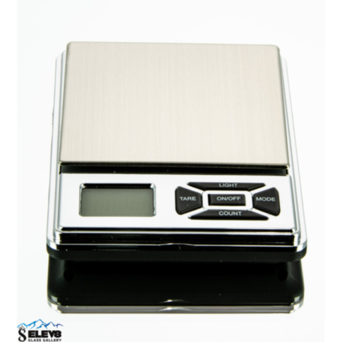 The Gripper 500 Scale 500g x 0.1g showcases a sleek metallic finish and a compact, portable design. This digital pocket scale is equipped with a clear display screen, buttons such as TARE and MODE, and features a stainless steel platform with an impressiv