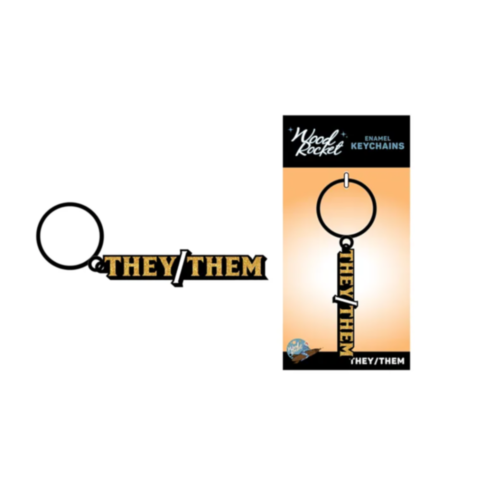 The Wood Rocket-The/Them Keychain is an enamel keychain displaying "They/Them" in bold black and yellow letters, attached to a keyring. It comes alongside packaging featuring the text "Wood Rocket Enamel Keychains.