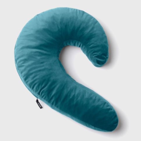 A blue, crescent-shaped Lune Side Snuggler Pillow with a soft, velvety texture is resting against a white background. Specifically designed for side sleeping, it features a small fabric tag on its side and is enhanced with plush memory foam for ultimate c