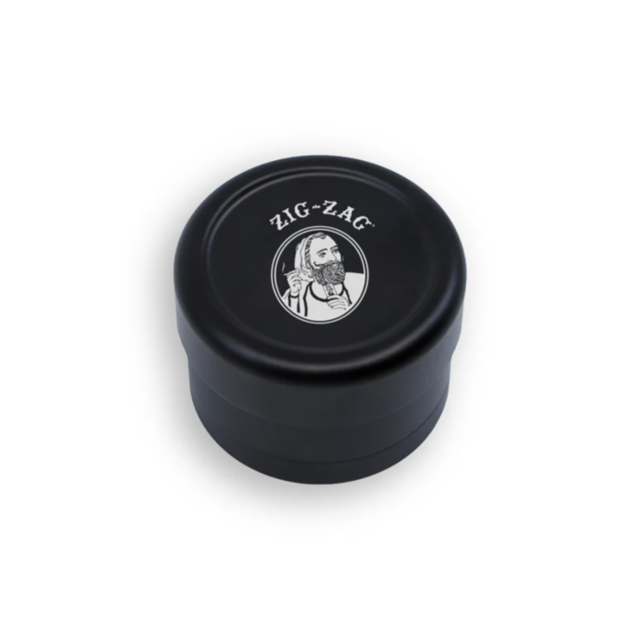 A sleek black plastic container featuring the Zig-Zag logo on the lid, with an illustration of a bearded man wearing a cap and smoking a pipe, matches perfectly with your 63mm 4pc Crushers Black Base ZigZag Grinder. This compact accessory is ideal for hol