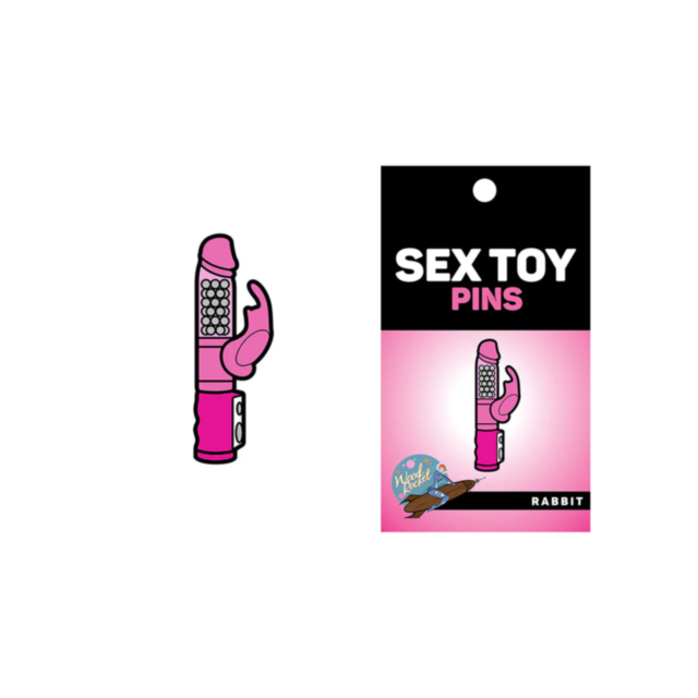 Illustration of the Wood Rocket-Rabbit Pin, a pink novelty enamel pin shaped like a rabbit-style vibrator, alongside its packaging labeled SEX TOY PINS. The packaging features an image that matches the pin and displays WoodRocket's colorful logo with a ch