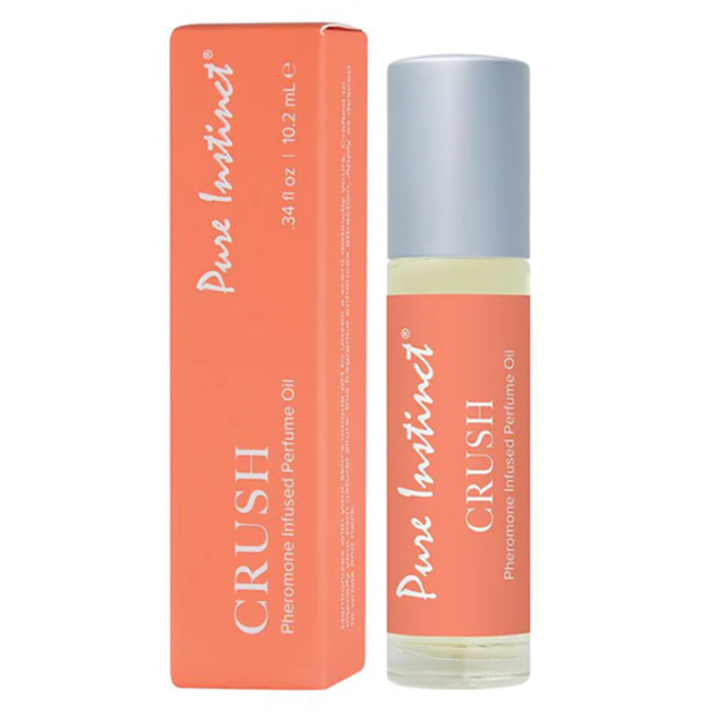 A bottle and box of Pure Instinct Crush Pheromone Oil, which boasts a seductive blend of amber and musk. The clear bottle, topped with a metal cap, is elegantly positioned next to its vibrant orange box adorned with white text, highlighting the fragrance'