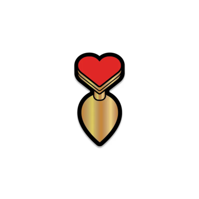 The Wood Rocket-Heart Butt Plug Pin is an enamel pin featuring a bomb with a red heart as its top, styled in gold for a minimalistic look. This edgy and bold accessory pops against a plain white background, adding a unique flair to any outfit.