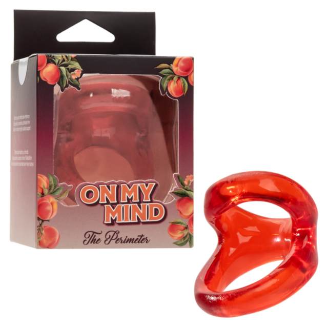 An orange novelty ring, On My Mind – The Perimeter, is shown beside its floral-designed box marked with the product name, emphasizing its function of providing dual support for enhanced erections.