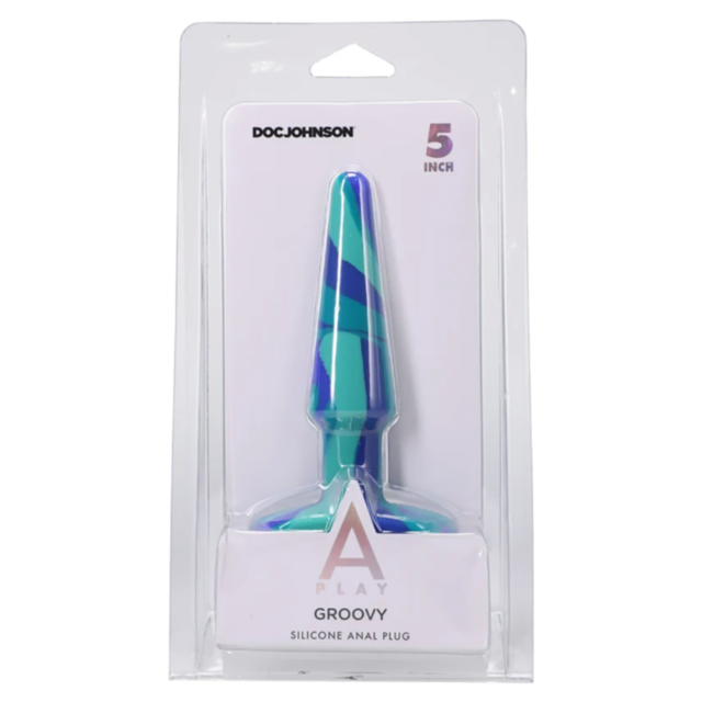 A stylized rocket ship flies upwards, surrounded by stars and curves, on a green square adorned with a gray graphic. Above this design, prominently displayed, are the words "Doc-A-Play Groovy Sil Anal Plug 5in-Ocean." The artwork maintains its hypoallerge