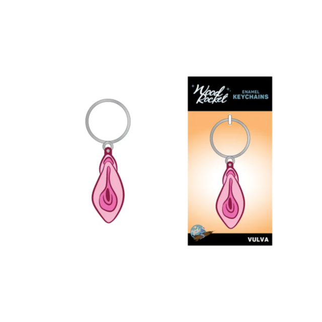 This unique accessory is the Wood Rocket-Vulva Keychain, featuring a glittery enamel charm and elegantly presented packaging. The packaging displays a sleek black top with "Wood Rocket Enamel Keychains" text set against a vibrant gradient orange backgroun