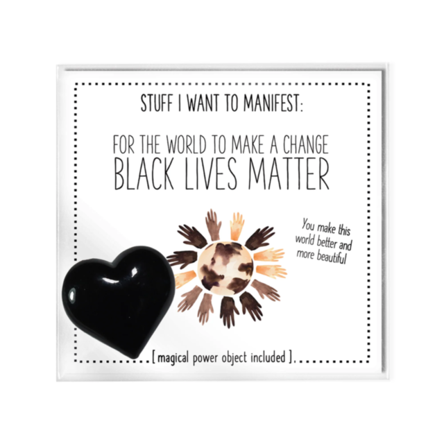 A white frame features the text: "Stuff I want to manifest: For The World To Make Change Black Lives Matter." Diverse hands form a circle around Earth, emphasizing racial justice. A black heart-shaped charm on the left is described as a magical power obje