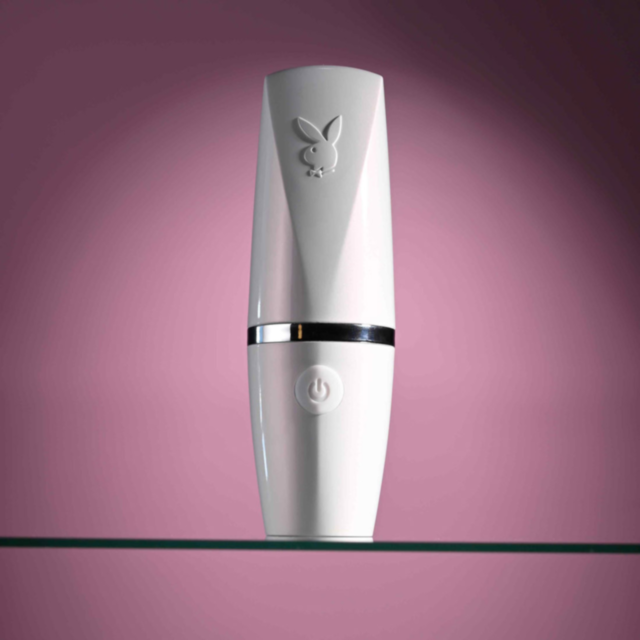Illustration of a rocket launching into space, surrounded by stars and a planet in the background, with the text "Evolved-Playboy Sil Rechargeable Getaway-White Opal" above. Crafted in body-safe silicone, the green background contrasts with the light gray