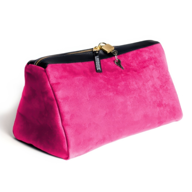 A vibrant fuchsia microsuede handbag with a triangular shape features a black zipper closure. A small gold padlock with a key, reminiscent of the Tallulah Locking Toy Case Microsuede-Fuchsia, adds a stylish accent as it rests on a white surface.